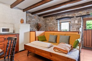A room with a wooden bed, a stone wall, a stone fireplace, a wooden cabinet, and a microwave.