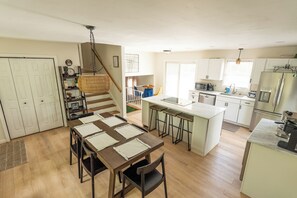 A modern kitchen with white cabinets, a central island, and a dining area with a wooden table and chairs.