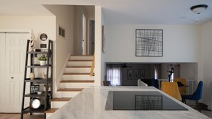 A modern living room with a marble coffee table, a bookshelf, and a staircase leading to an upper level.