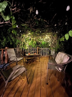A wooden deck with wicker furniture and a white railing. - Private Hot Tub, Deep Pool, Fire Pit, 3 King, 1 Queen, TV!! (Raleigh)
