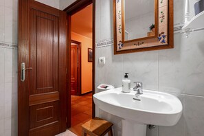 A bathroom with a wooden door, a white sink, and a mirror with a decorative frame.