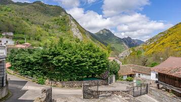 Un villaggio montano con edifici in pietra, una strada asfaltata e un cancello.