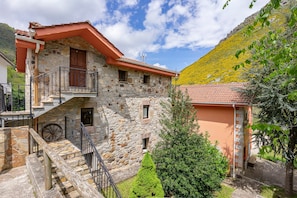 A stone building with a balcony, a wooden staircase, and a small window.