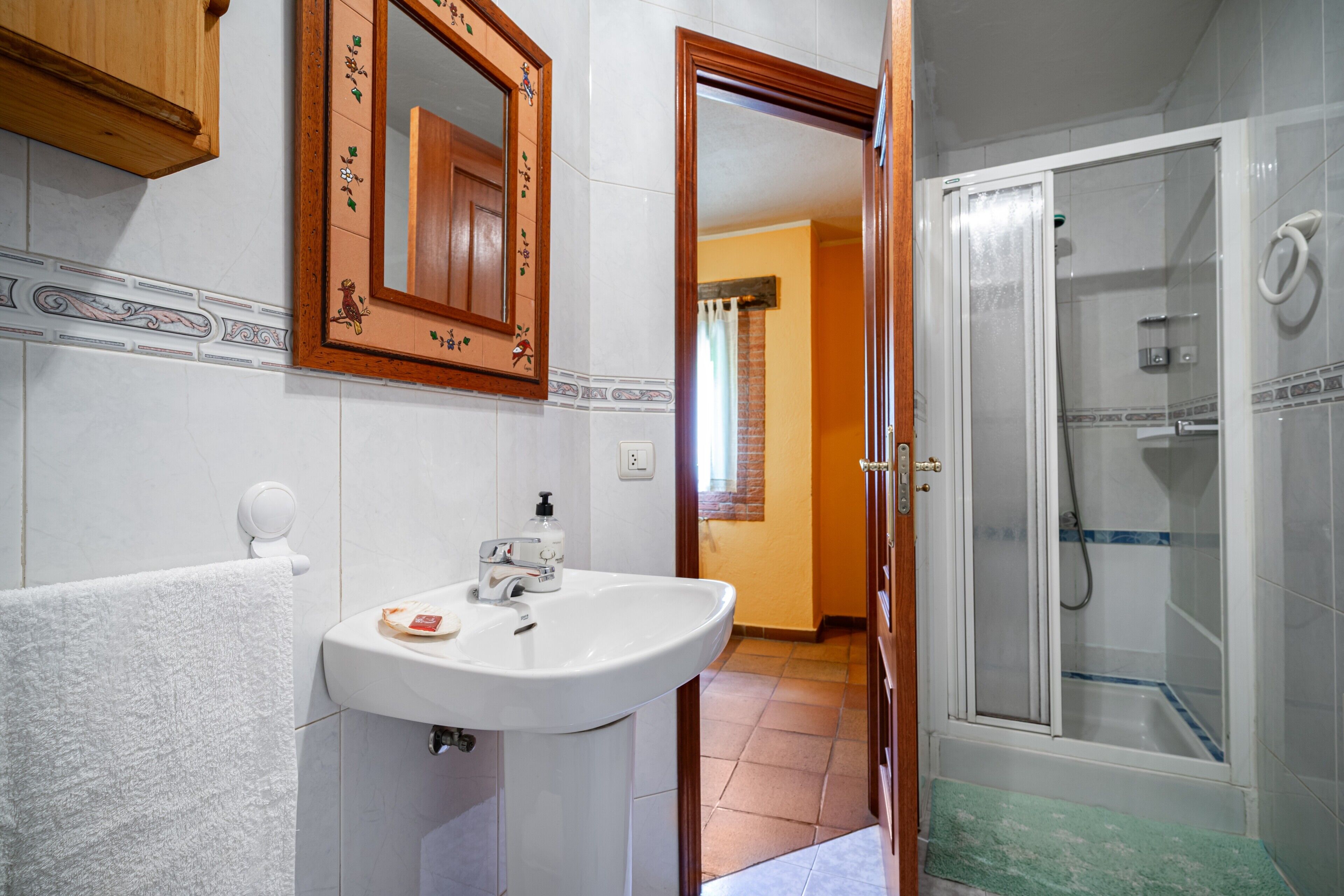 A bathroom with a sink, mirror, and shower.