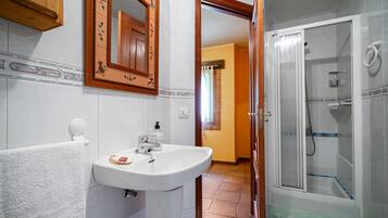 A bathroom with a sink, mirror, and shower.