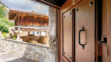 A wooden door with a metal handle and a keyhole, part of a building with stone walls and a tiled roof.