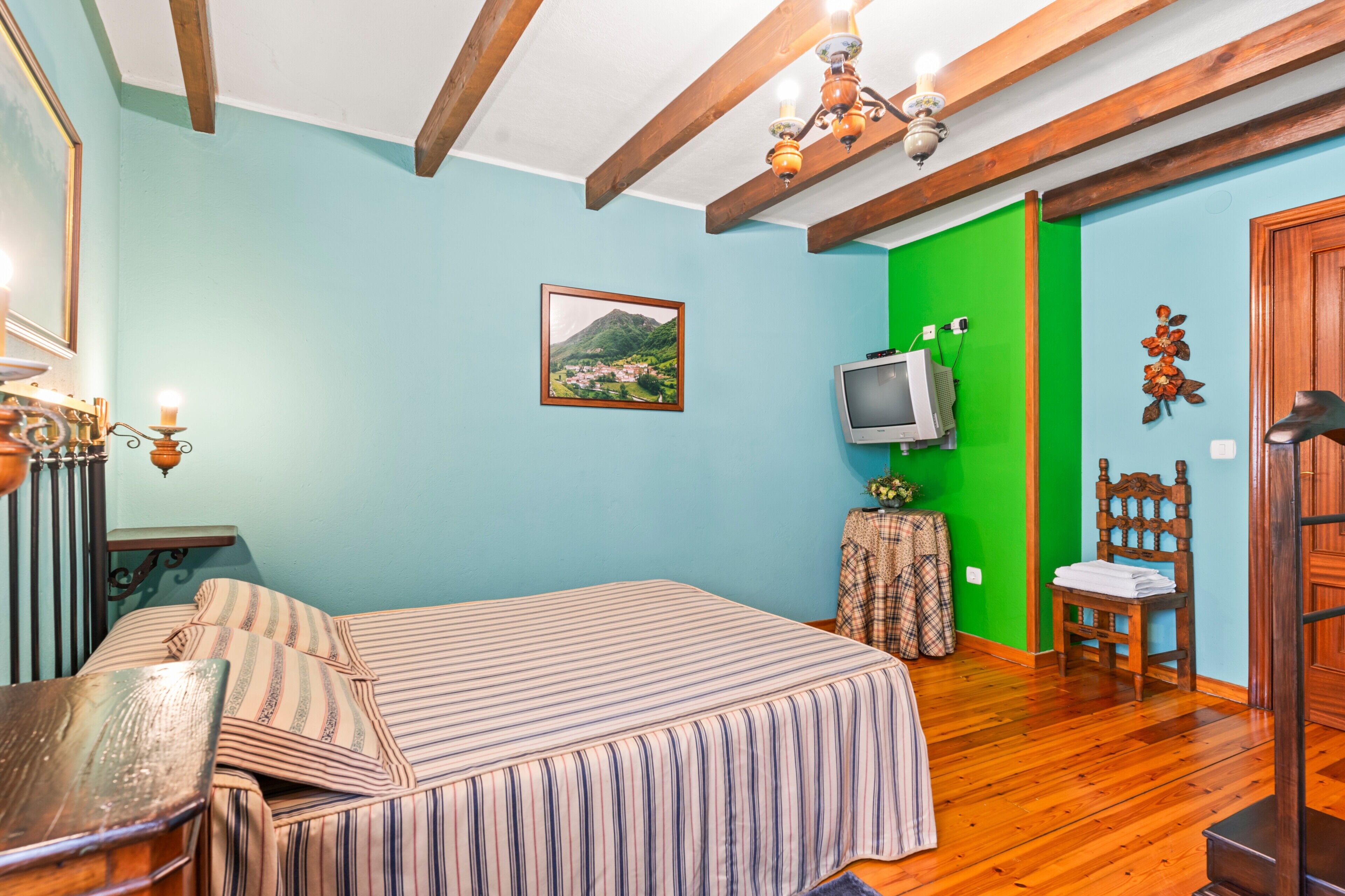 Ein Schlafzimmer mit einem Bett, einem Fernseher, einem Sessel und Holzboden.