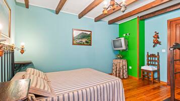 Ein Schlafzimmer mit einem Bett, einem Fernseher, einem Sessel und Holzboden.