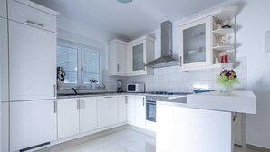 A modern kitchen with white cabinetry, a central island, and a microwave.