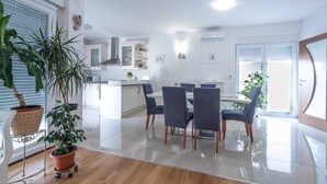 A modern kitchen with white cabinetry, a central island, and a dining area with four chairs.