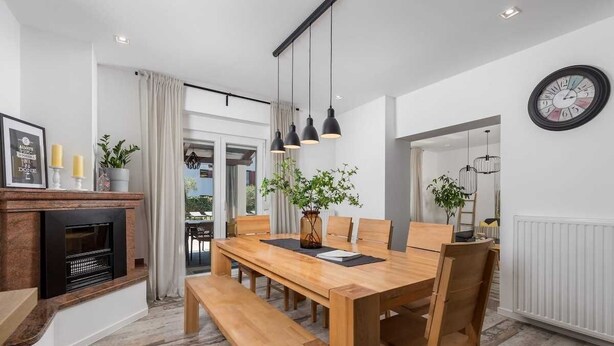 Un comedor con una mesa de madera, bancos y lámparas colgantes.