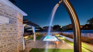 A swimming pool with a water feature, surrounded by a stone wall and a pergola. - Villa Marcela | Adriatic Luxury Villas (Pridraga)