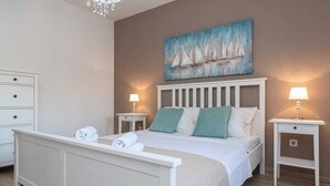 A neatly arranged bedroom with a bed, two bedside tables, a nightstand, and a wall-mounted painting. - Villa Marcela | Adriatic Luxury Villas (Pridraga)