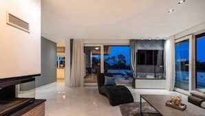 Un salon moderne avec un téléviseur à écran plat, un canapé noir et une table basse en verre.