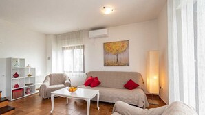 A living room with a beige sofa, a white coffee table, and a painting on the wall.