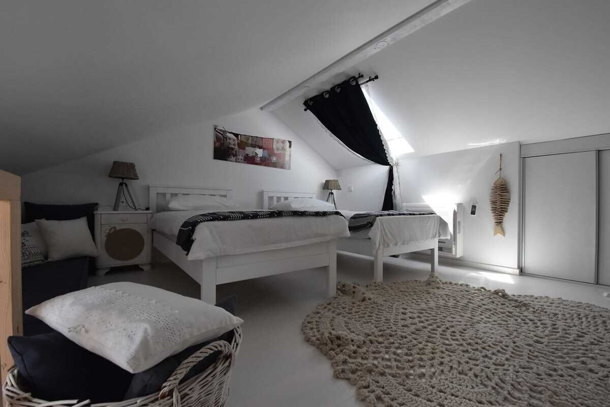 Ein Schlafzimmer mit zwei Betten, einem großen Fenster und einer Wanddekoration.