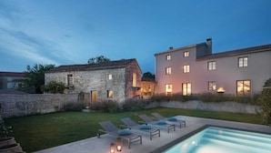 Una casa moderna con piscina, muros de piedra y un patio bien iluminado.