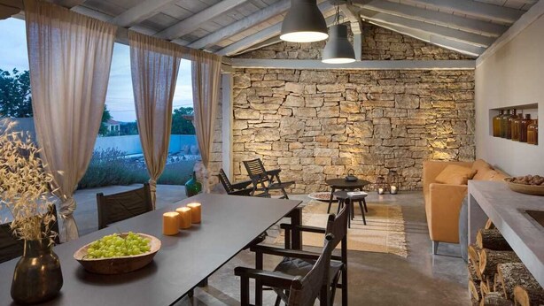 Un comedor acogedor con pared de piedra, muebles de madera y vistas al exterior.