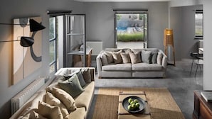 Una sala de estar moderna con un sofá, una mesa de centro con manzanas y vistas a un jardín a través de grandes ventanales.