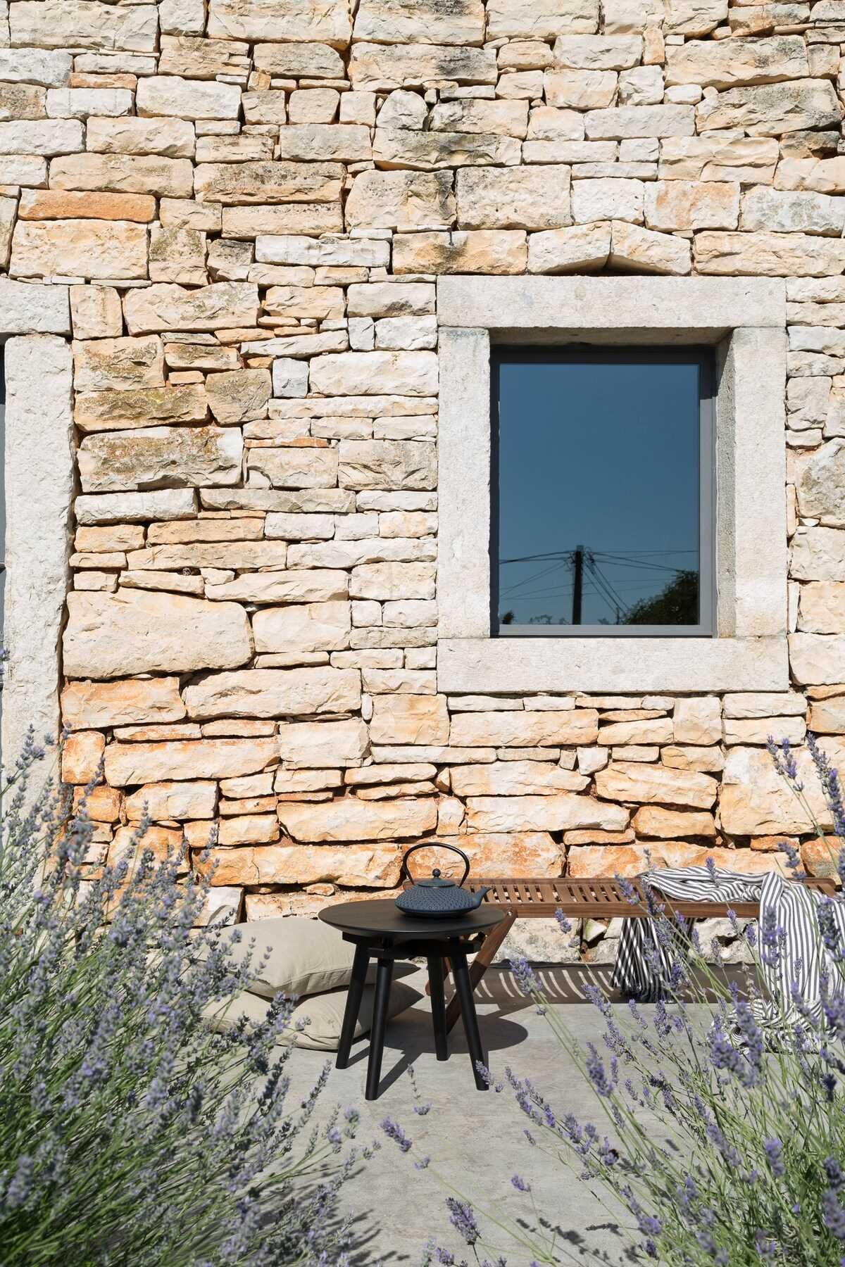 A stone wall with a window and a table with a teapot.