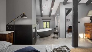 Un dormitorio moderno con una cama grande, un escritorio y vistas a un baño con bañera.