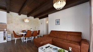 Una sala de estar moderna con un sofá de cuero marrón, una mesa de centro de vidrio y un candelabro.