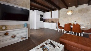 Una cocina moderna con armarios blancos, horno integrado y zona de comedor con sillas marrones y mesa blanca.