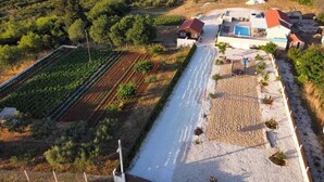 Vista aérea de una propiedad con piscina, un jardín grande y un camino que lleva a una casa.