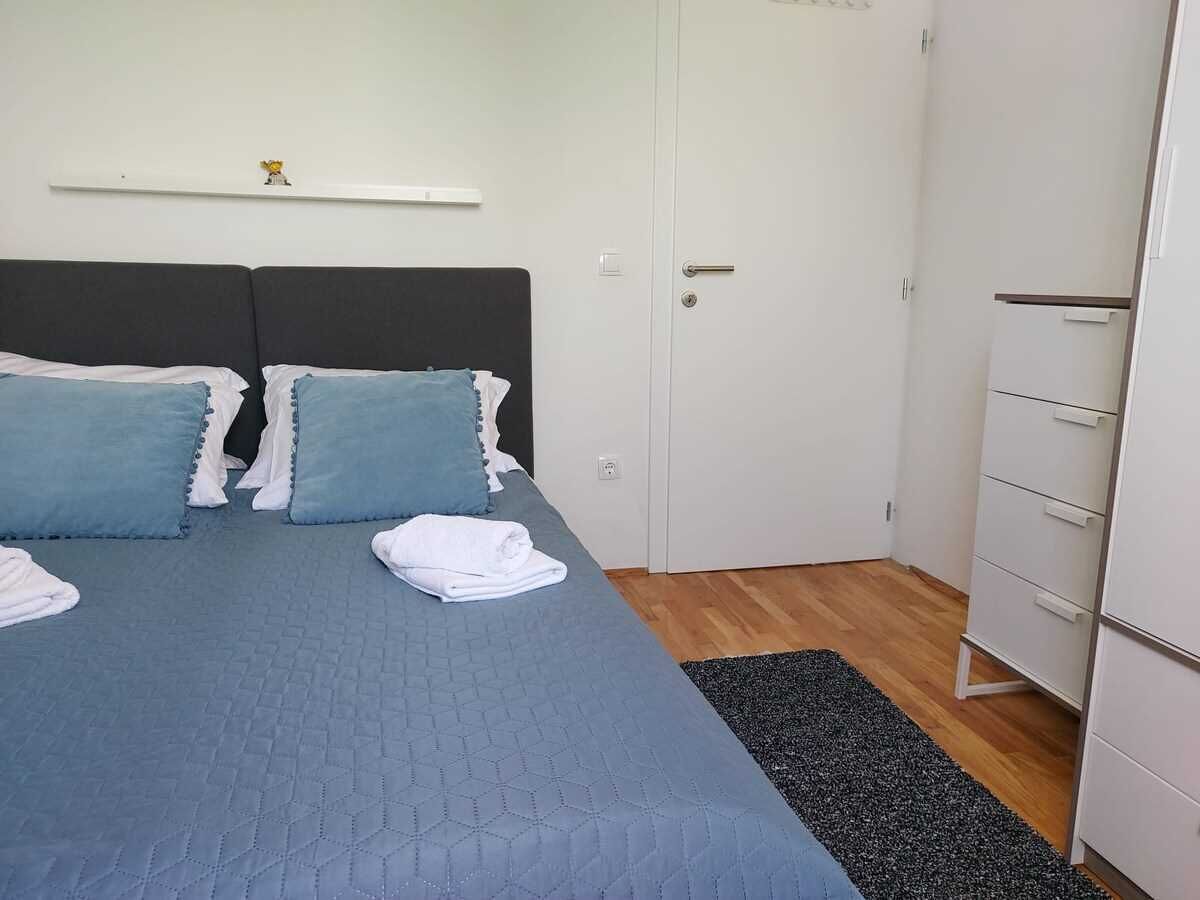 Ein Schlafzimmer mit einem Bett, Kissen, einem weißen Kleiderschrank und einer kleinen Ablage mit einer Figur.