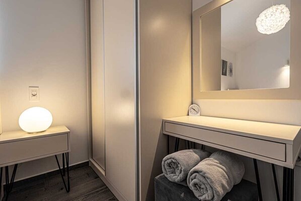 A modern bathroom with a vanity, a mirror, a round light, and a clock.