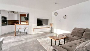 Una sala de estar moderna con un sofá, una mesa de centro y un televisor montado en la pared.