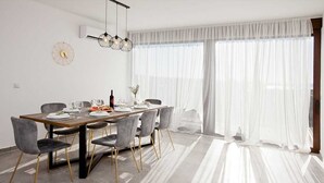 Un comedor con una mesa de madera, sillas tapizadas de color gris y una araña.