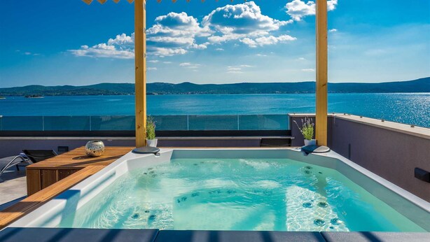 A hot tub with a view of a large body of water and mountains in the background.