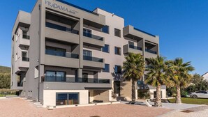 A multi-story building named "FRADAMA blue" with balconies, a covered entrance, and palm trees in the foreground.