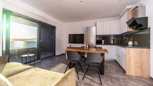 A modern kitchen with a wooden dining table, grey chairs, and a built-in oven.