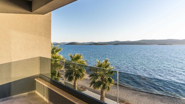 A balcony with a view of a calm sea and distant hills.