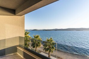 Un balcón con vista a un mar tranquilo y colinas lejanas.