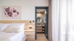 A modern bedroom with a bed, a nightstand, a wall-mounted light, and a bathroom visible through an open door. - Villa Dekorti | Adriatic Luxury Villas (Kožino)