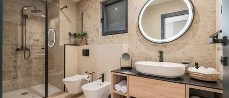 A modern bathroom with a glass-enclosed shower, a bidet, a sink with a mirror, and wooden cabinets.