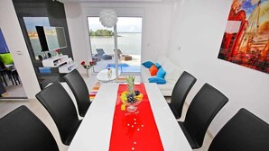 Un comedor moderno con una mesa larga, sillas negras y un corredor rojo.