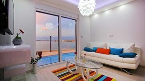 Una sala moderna con un sofá blanco, un tapete a rayas de colores y una mesa de centro de cristal.