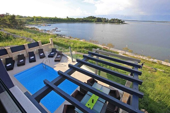 A pool area with lounge chairs and a view of a lake.
