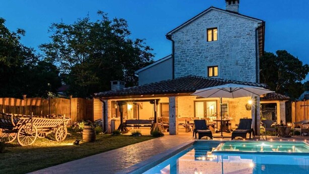 A stone building with a pool and outdoor seating area.