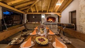 A wooden dining table set for a meal with a fireplace in the background.