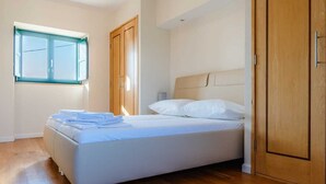 A bedroom with a bed, wooden wardrobe, and a window.