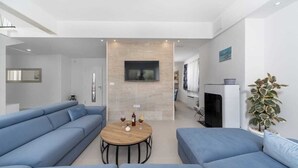 Una sala de estar moderna con un conjunto de sofás, una mesita de centro y un televisor de pantalla plana montado en la pared.