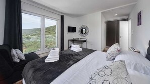 Un dormitorio con una cama grande, un televisor, un espejo y vistas al exterior.