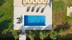 Vista aérea de un área de piscina con sillas de descanso y una terraza.