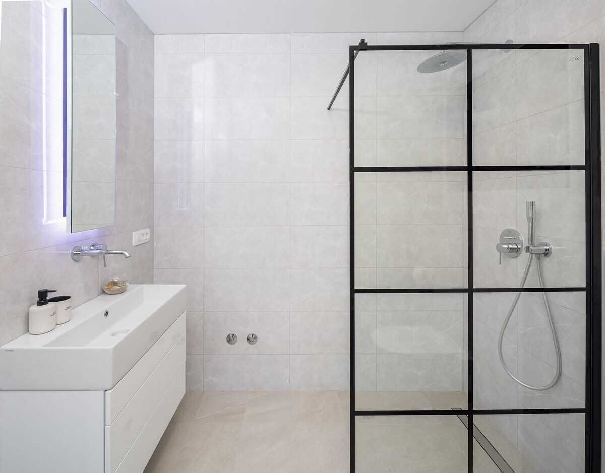 Une salle de bain moderne avec une douche à parois de verre, un meuble-lavabo blanc avec un miroir et des toilettes.