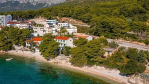 Un pueblo costero con edificios modernos, una playa y montañas al fondo.